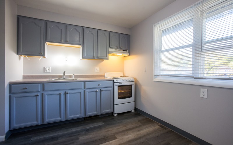 Two-bedroom kitchen with blue cabinets and window at Carriage House Apartments, Syracuse NY