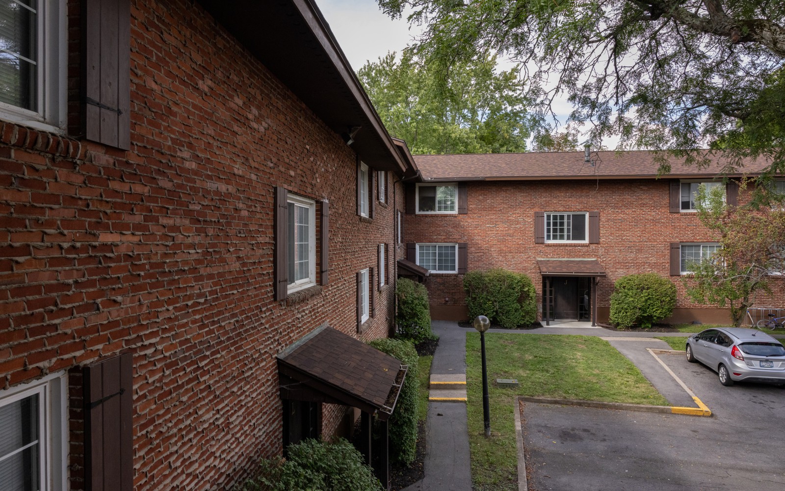 Two-story brick apartment buildings around a lawn and walkway at Carriage House Apartments, Syracuse NY