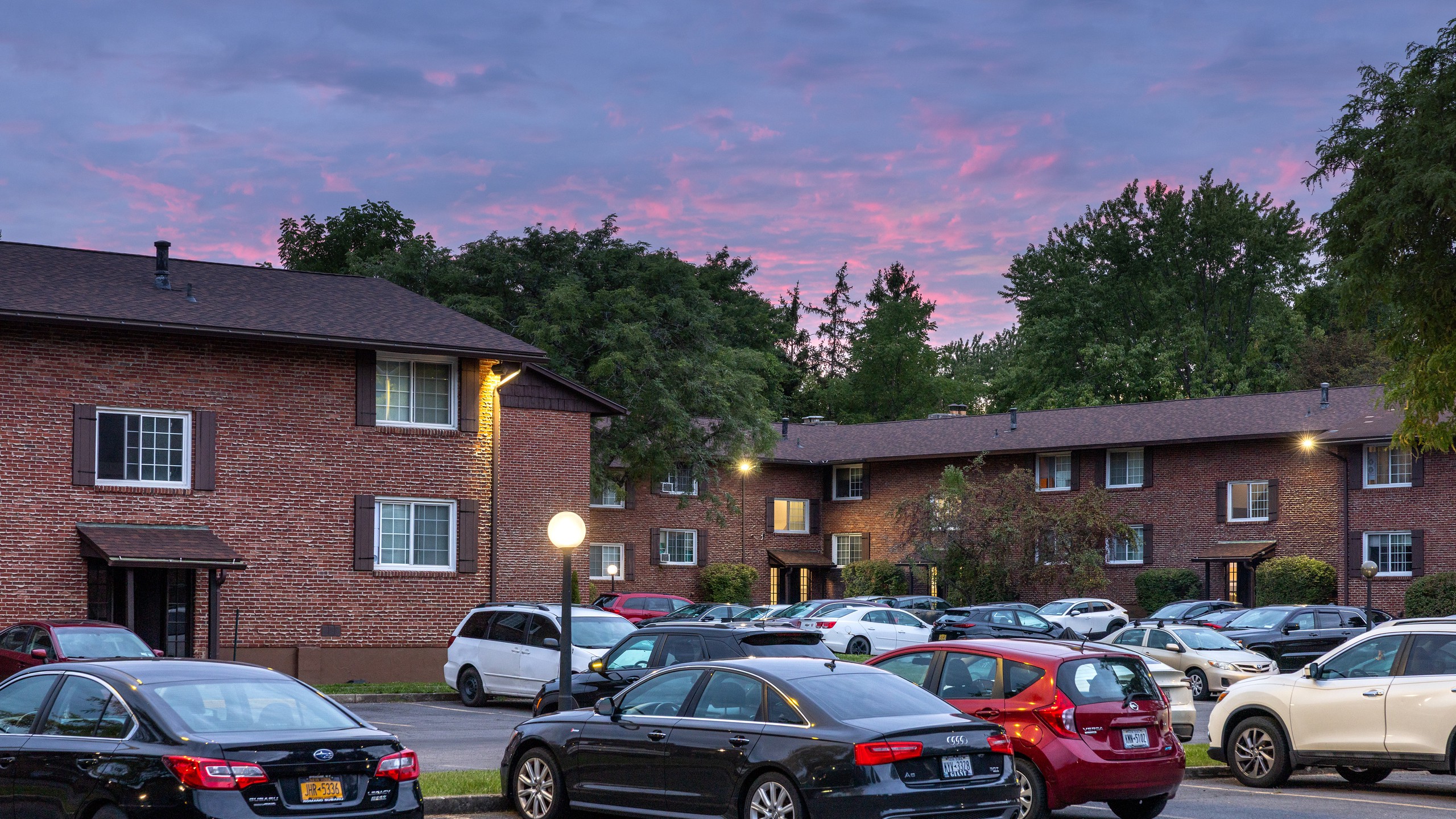 Brick apartment buildings and parking lot at dusk at Carriage House Apartments, Syracuse NY