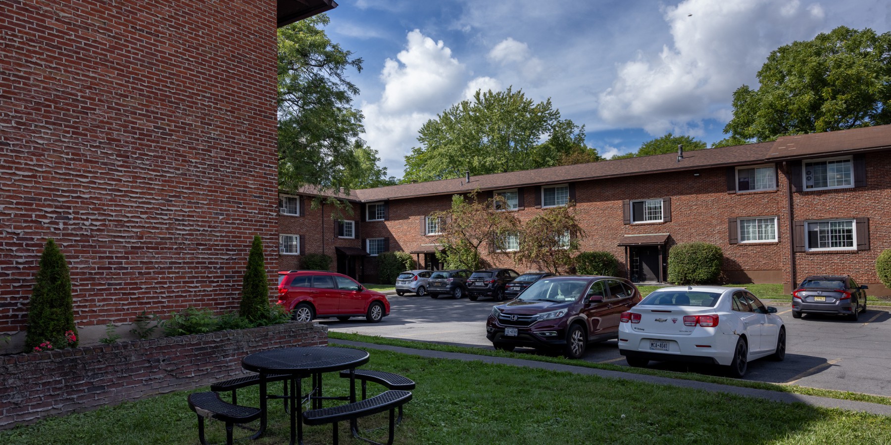 Picnic table on the lawn beside brick buildings and the courtyard at Carriage House Apartments, Syracuse NY