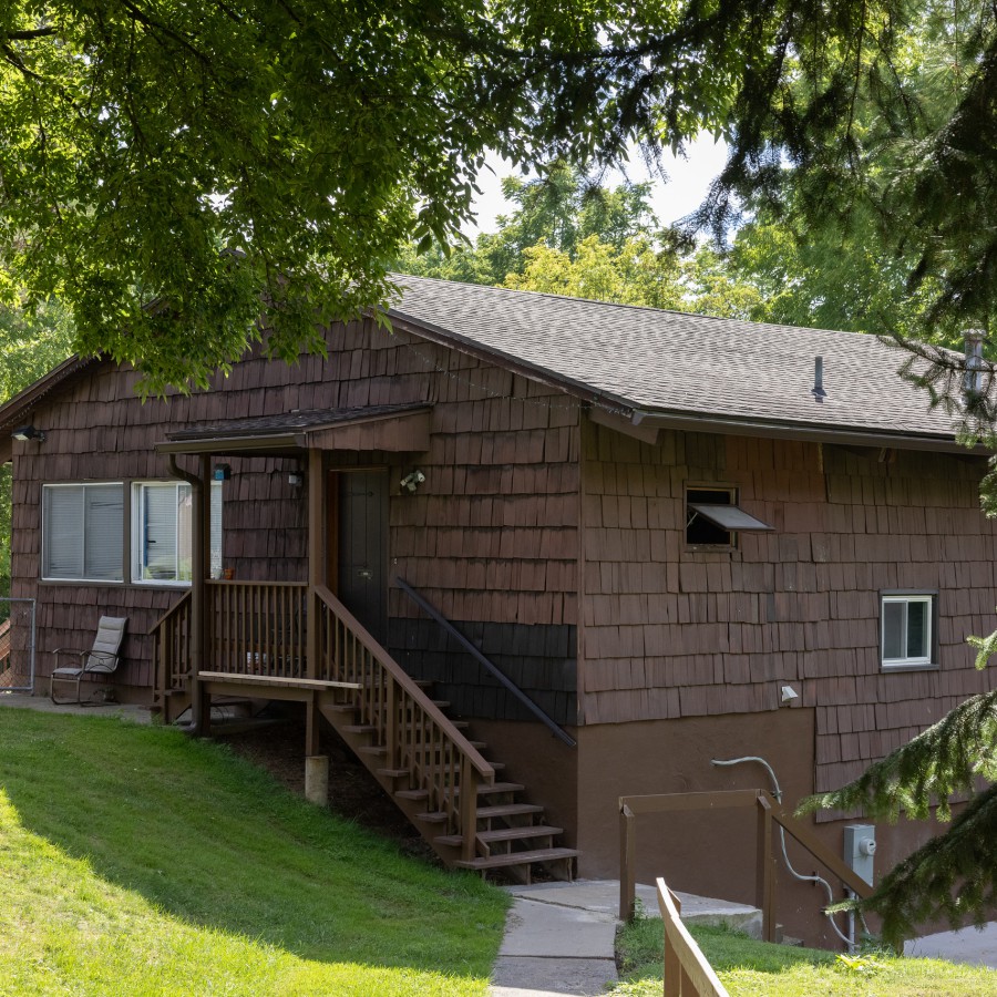 Brown shingle private home with a front porch among trees at Carriage House Apartments, Syracuse NY